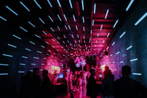 Personen tanzen in einem künstlich beleuchteten Raum ohne Fenster