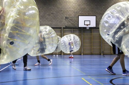 Jugendliche spielen Bubble-Fussball in einer Turnhalle