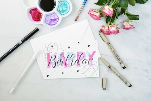 Verschiedene Stifte und Farben liegen neben einer selbstgemachten Geburtstagskarte